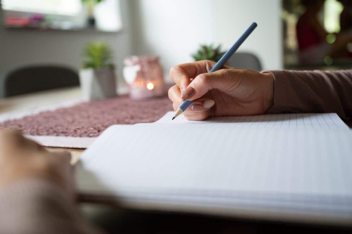 journalling to help reconnect with your goals Woman journalling at home with pencil and notebook, taking time to reconnect with your goals