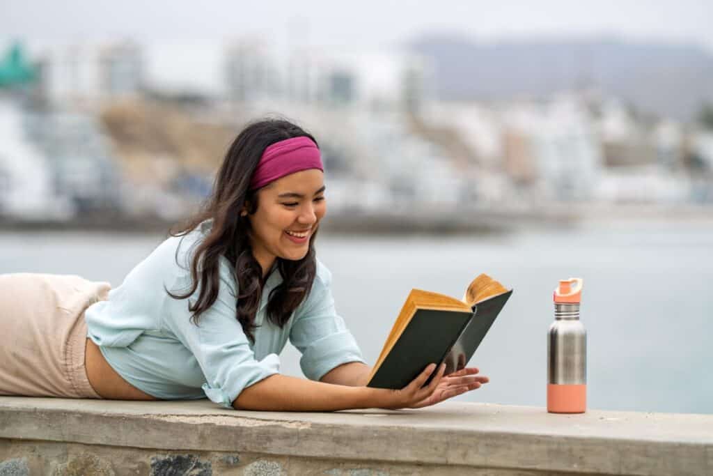 Woman reading and reflecting in a journal outdoors during a peaceful moment